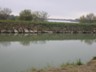 The current electric pump station raises water 42 feet from the Rio Grande River to this canal.  The water flows into the holding lake behind the canal wall in the photo.  From there the water flows in an underground canal, 15 miles to Edinburg , Texas. Once the water has been pumped out of the river, gravity moves it inland. 